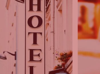 artigo: Covid-19 e o cancelamento de reservas em hotéis: O que fazer ? Na foto, a fachada de um hotel. Cores na imagem: preto, branco e laranja.