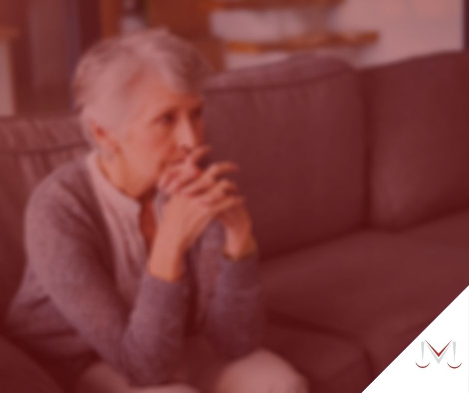 #pratodosverem: post: Pensão por morte é direito de quem da família? Na foto uma idosa sentada no sofá com as mãos na cabeça. Cores na imagem: vermelho, cinza, marrom e branco. 