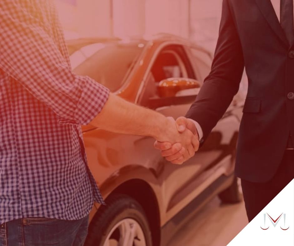 #pratodosverem: artigo: Os dez passos para celebrar uma compra de veículo bem sucedida. Na foto, duas pessoas apertando a mão uma da outra, concretizando uma negociação. Cores na imagem: preto, roxo, branco, dourado.