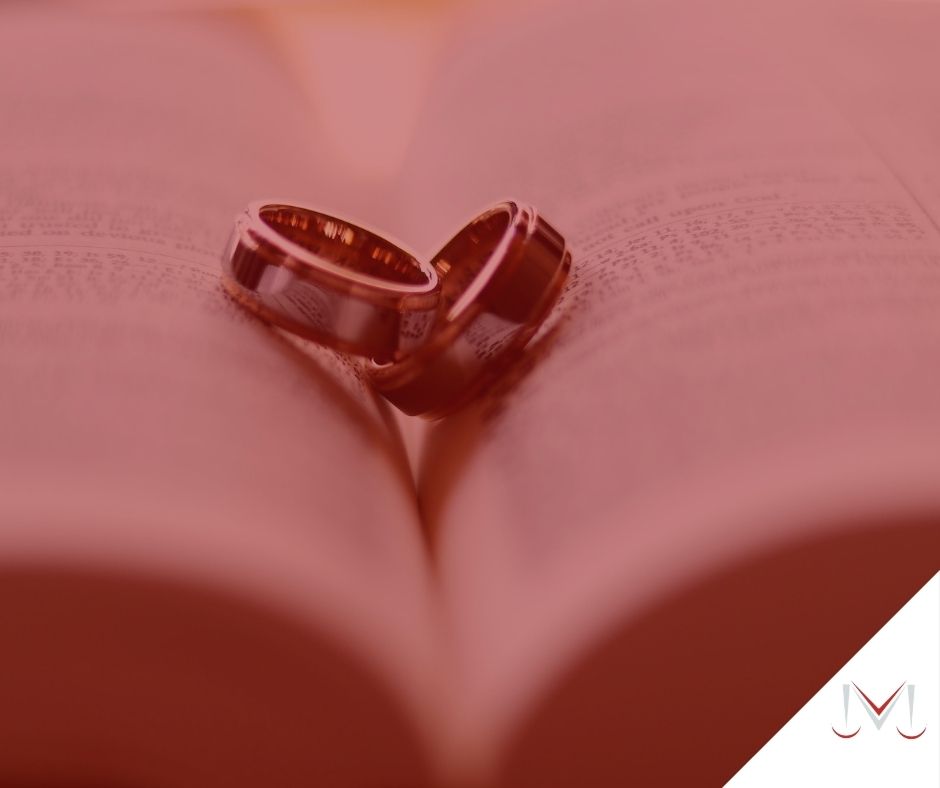 #pratodosverem: artigo: Os impedimentos matrimoniais. Descrição da imagem: Um livro com duas alianças em cima. Cores na foto: dourado, prata, branco, preto, cinza e vermelho. 