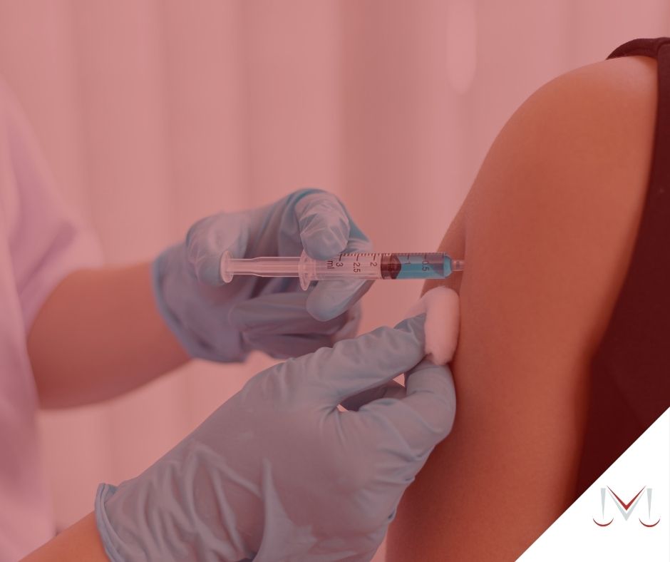 #pratodosverem: artigo: Demissão de não vacinados. Descrição da imagem: uma enfermeira está aplicando a vacina em outra pessoa. Cores na foto: azul, preto, branco, cinza e vermelho. 