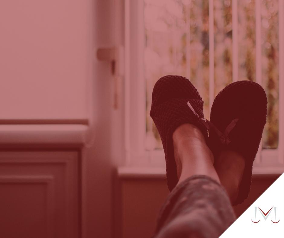 #paratodosverem: artigo: Descanso semanal remunerado. Descrição da imagem: uma pessoa com os pés apoiados no encosto do sofá. Cores na foto: marrom, preto, cinza, vermelho e branco. 