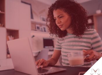 #paratodosverem: artigo: Novas regras para o trabalho home oficce. Descrição da imagem: uma mulher mexendo no computador em casa e tomando café. Cores na foto: branco, verde, marrom, laranja, cinza e vermelho.