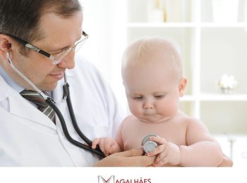 #pratodosverem: artigo: Pediatria na Unidade de Pronto Atendimento – UPA. Descrição da foto: um médico realizando atendimento em um recém nascido. Cores na foto: branco, preto, cinza, vermelho, branco e verde.